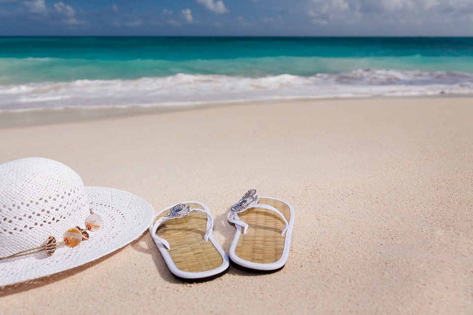 Paire de tongs et chapeau de paille posés sur la plage en bord de mer