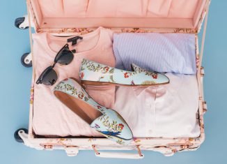 Valise remplie pour les vacances avec des t-shirts, des lunettes de soleil et des chaussures fleuries